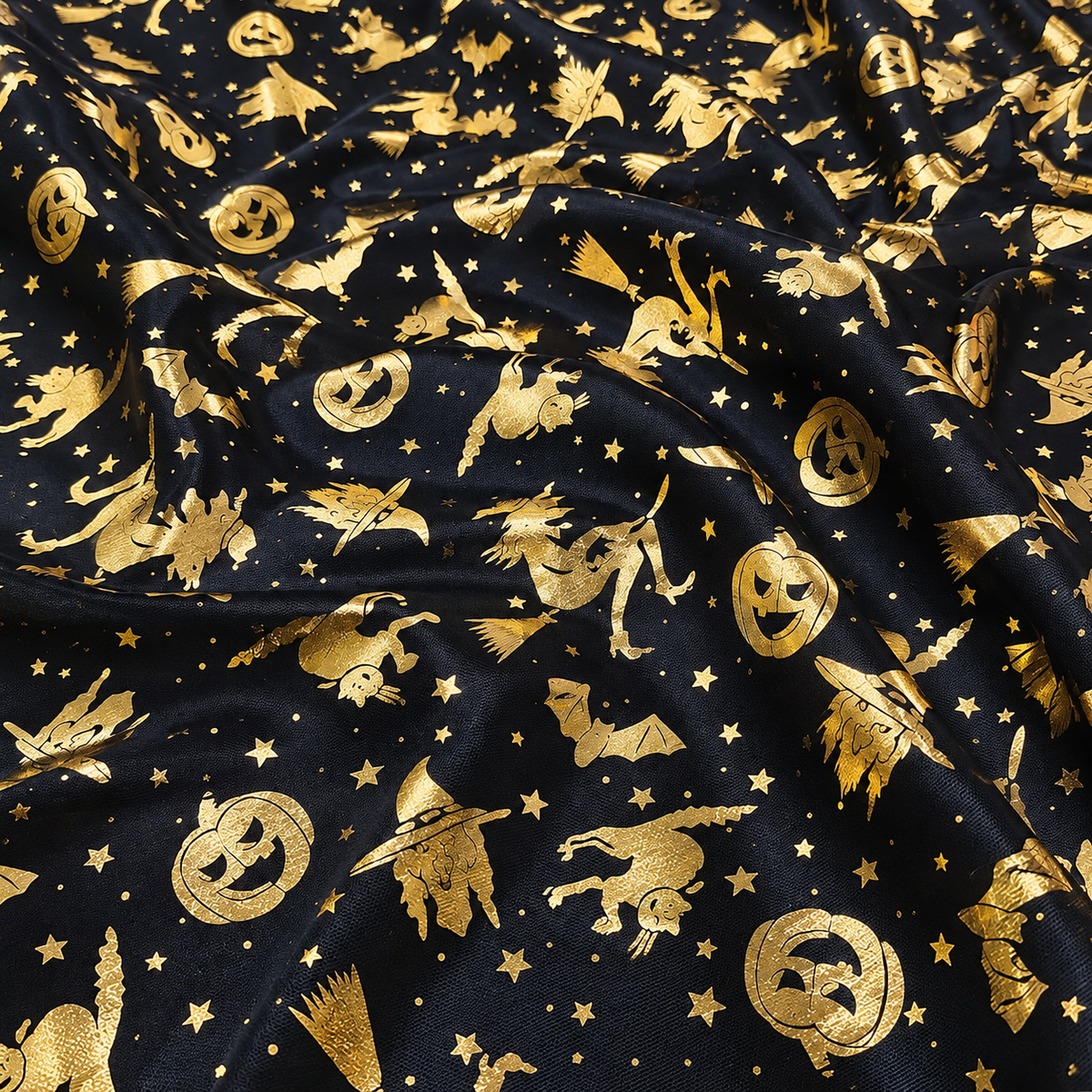 Black fabric with a gold foil Halloween pattern featuring witches, pumpkins, bats, and stars.