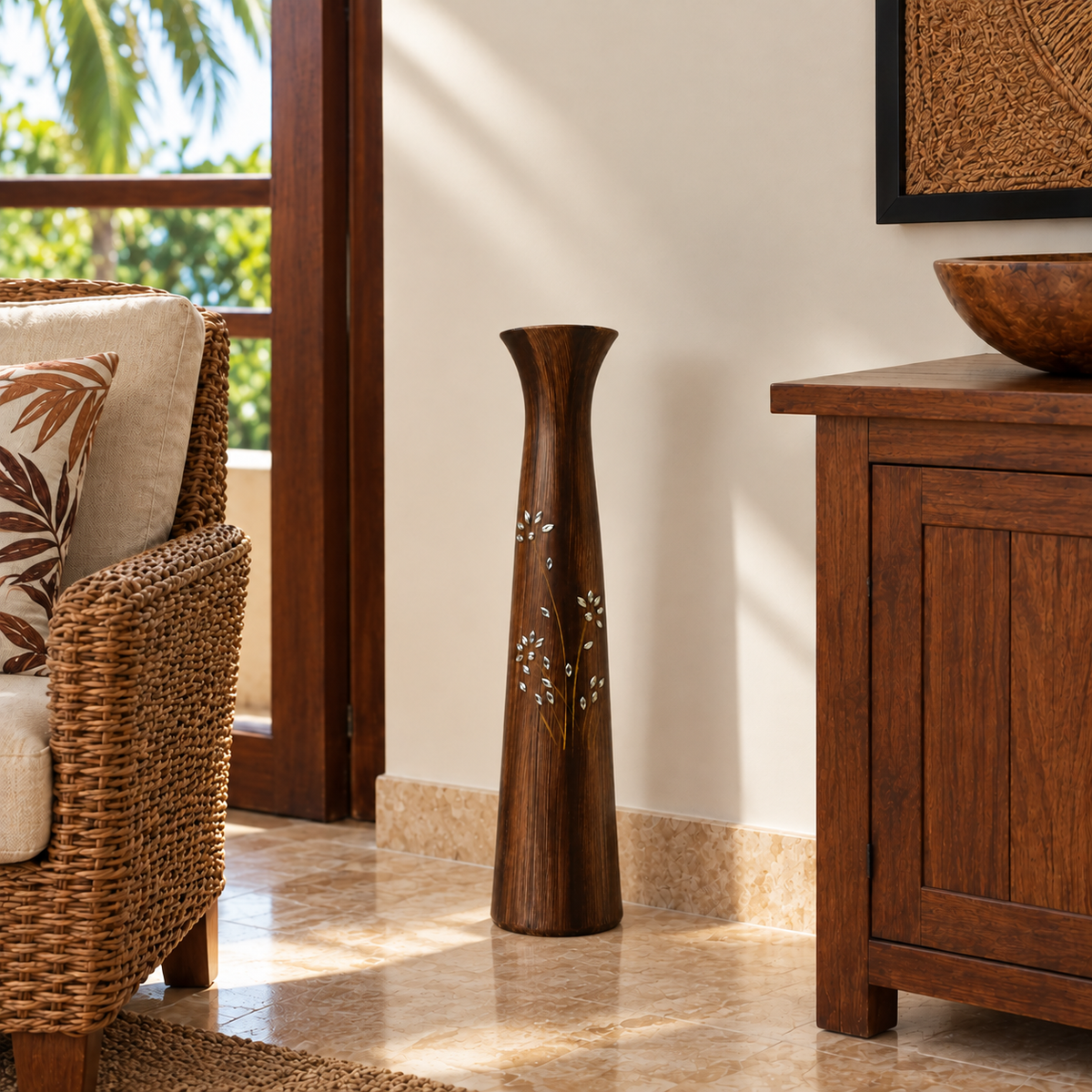 A tall, dark brown wooden decorative vase with white floral inlay, standing on a tiled floor in a warm, sunlit room next to a wicker chair and wooden cabinet.