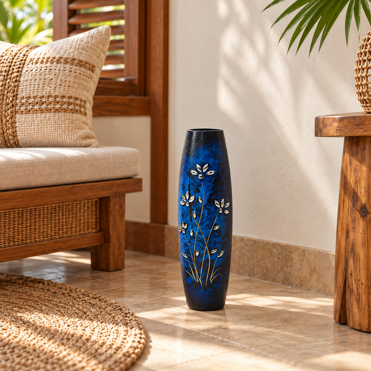 A tall, dark blue ceramic vase with white floral patterns stands on a tiled floor in a sunlit, rustic living room setting.