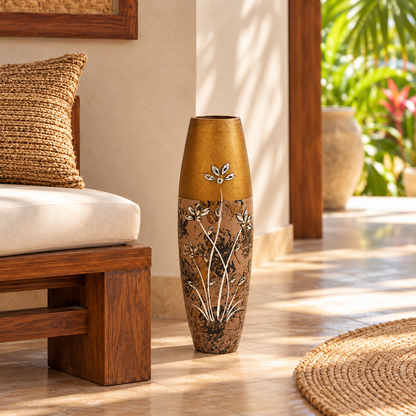 A tall decorative ceramic vase with a metallic gold top and a brown floral body, placed on a tiled patio beside a wooden bench in a sunlit indoor-outdoor setting.
